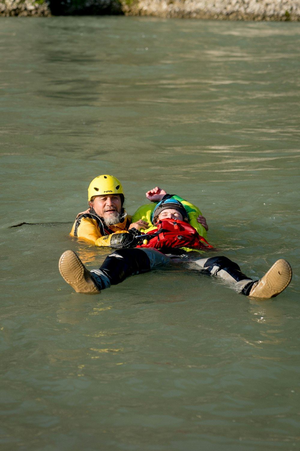 Chico con casco y chaleco flotando en el río junto a un guía